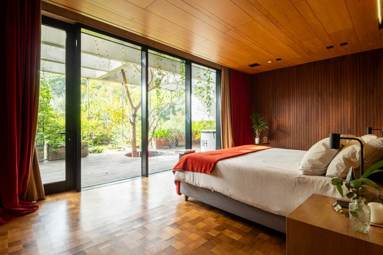 Dormitorio principal revestido en madera con ventanal al parque