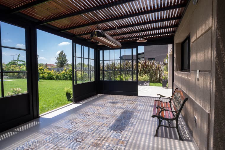 Galería con pérgola de madera y piso de baldosas calcáreas