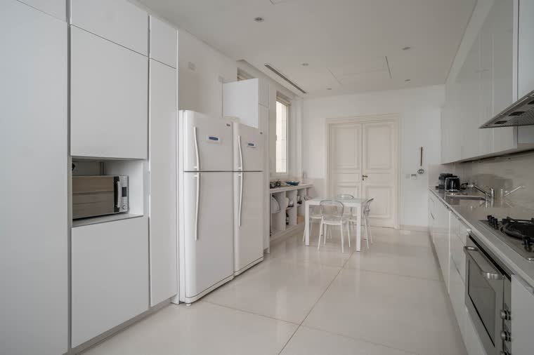 Cocina blanca con mesa y acceso al office